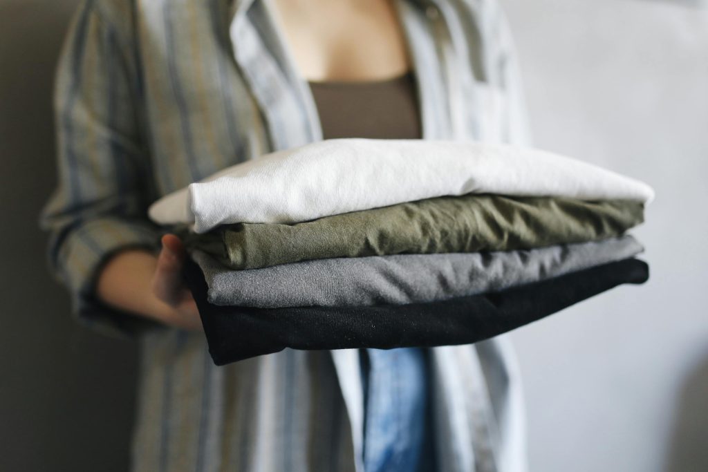 pexels photo 4440574 4440574 A close-up of a person holding neatly folded shirts, perfect for home organization themes.